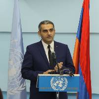 Suren Manukyan at a podium with the Armenian flag behind him.