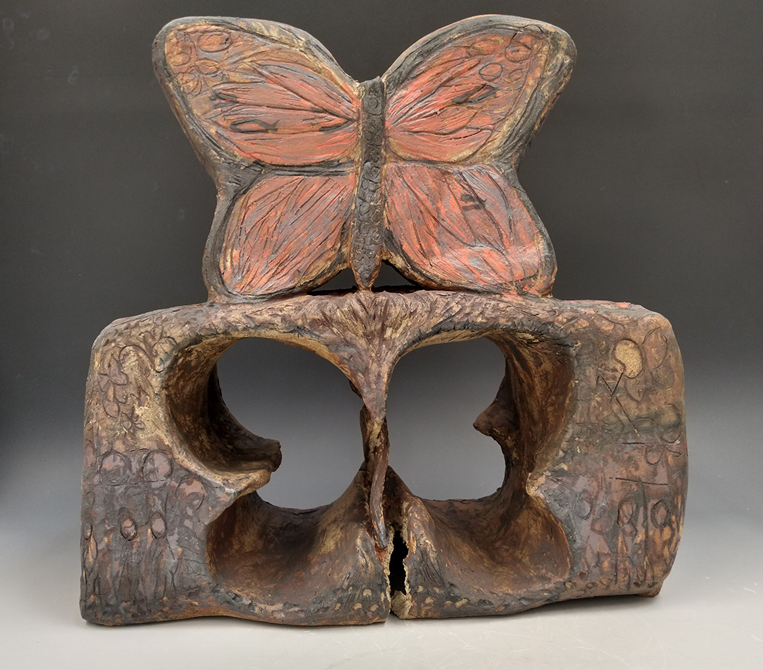 Cermic sculpture of a butterfly atop a square with the shape of the butterfly cut out