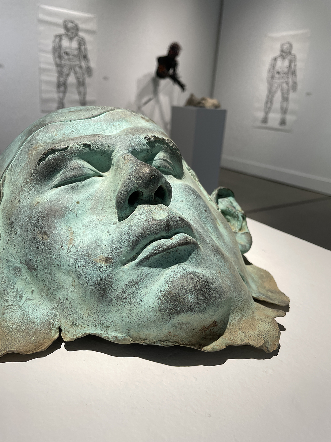 Patinad bronze mask of face in an art gallery