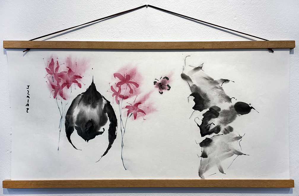 ink wash painting of two bats, one hanging and one flying with three pink flowers and a butterfly. painting is hung on a while wall with a wooden frame