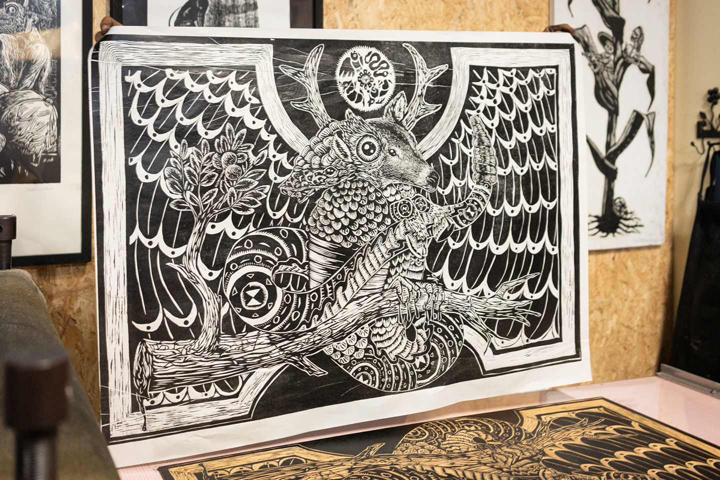 relief print of an animal hybrid being held above a printing press