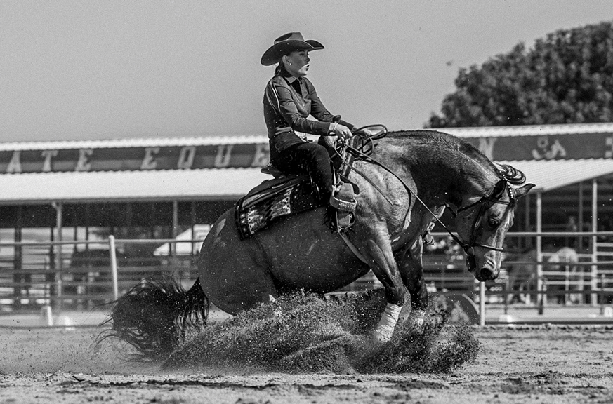 Black and white photo of woman riding a bucking horse
