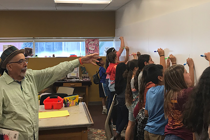 Professor Juan Felipe Herrera directs a group of schoolkids to create poetry and art on the walls.