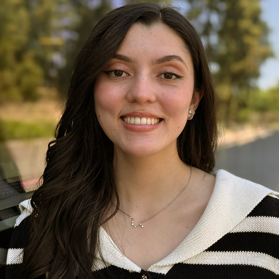 Headshot of Wendy with windows and greenery in background.