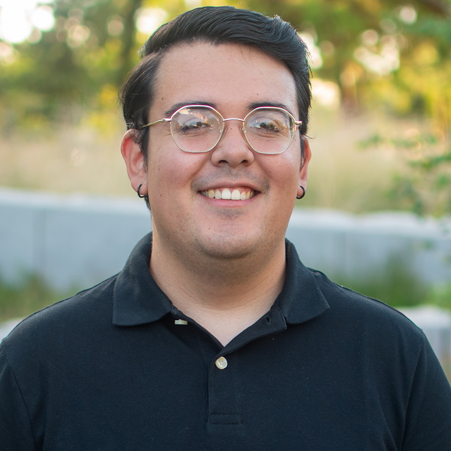 Headshot of Christopher with greenery in background.