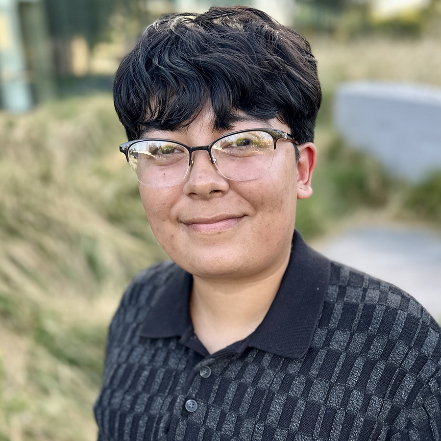 Headshot of Jacquelyn with greenery in background.
