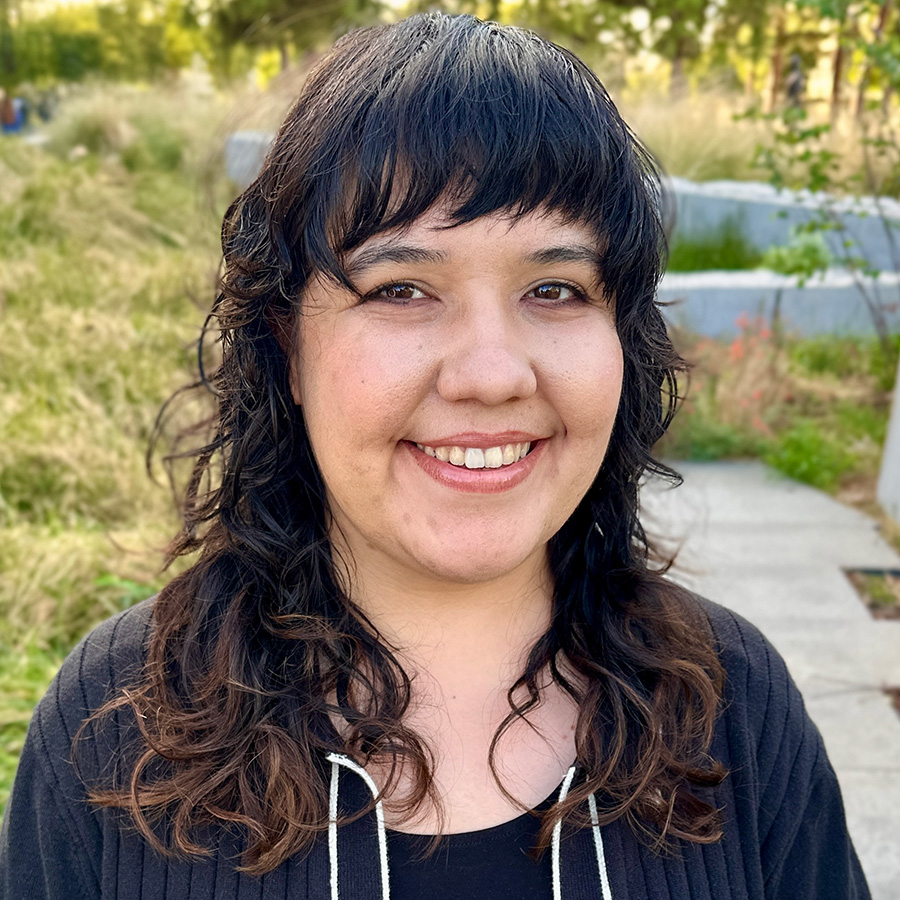 Headshot of Julia with greenery in background.