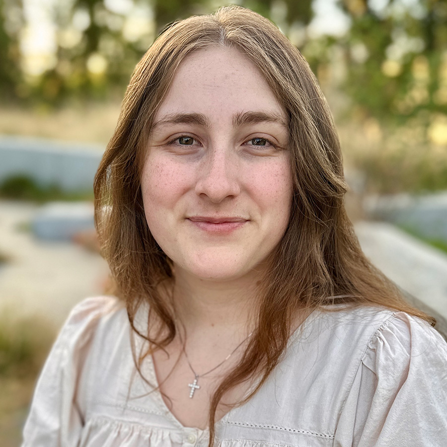 Headshot of Sylvia with greenery in background.