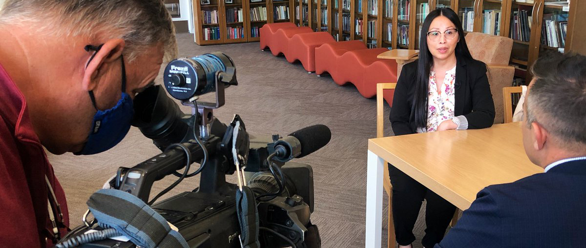 Professor Mai Der Vang is interviewed by an ABC30 reporter and photographer inside the Philip Levine Reading Room