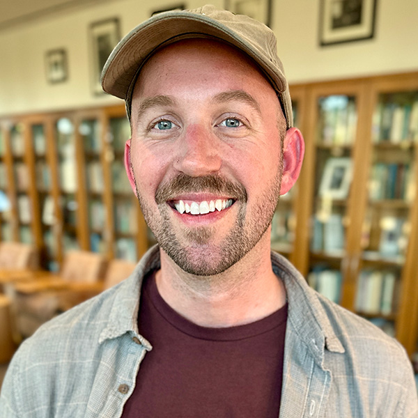 Headshot of Alexander with books on bookshelves in background.