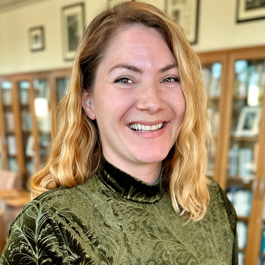 Headshot of Anya with books on bookshelves in background.