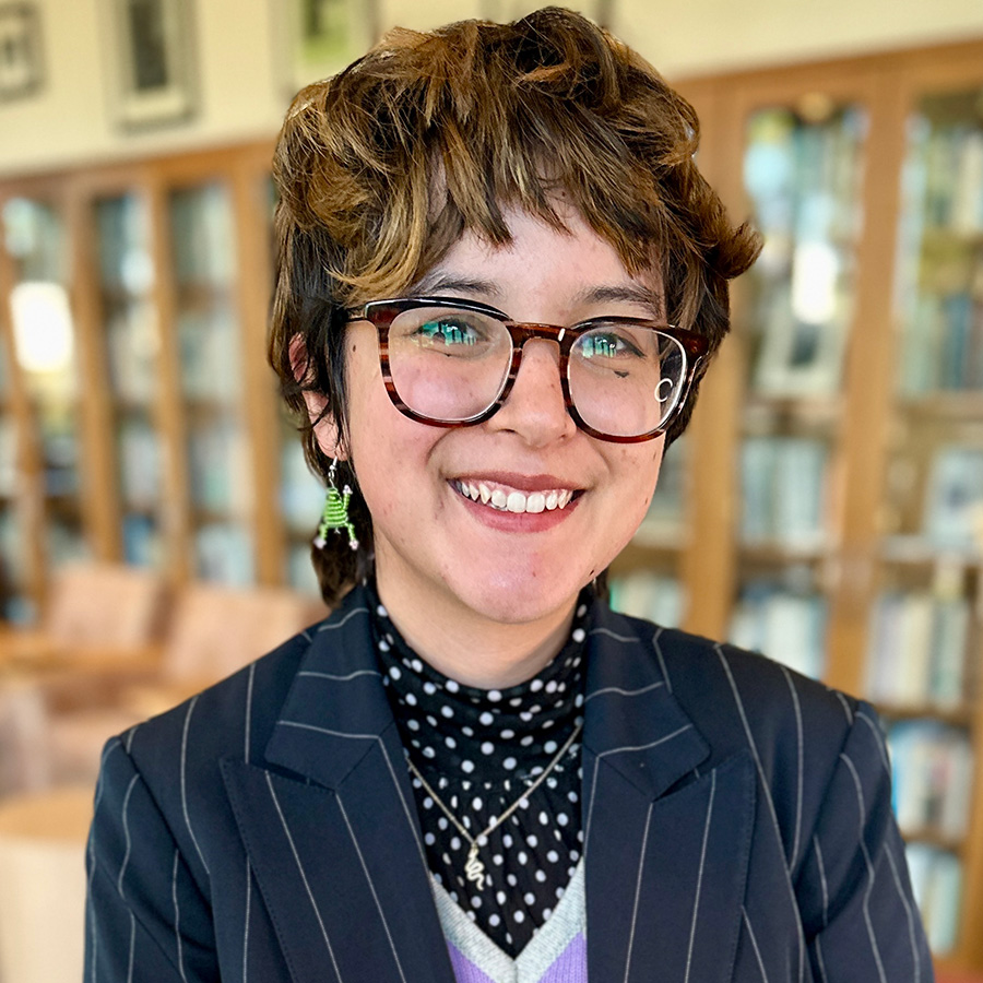 Headshot of Emerald with bookshelves in background.