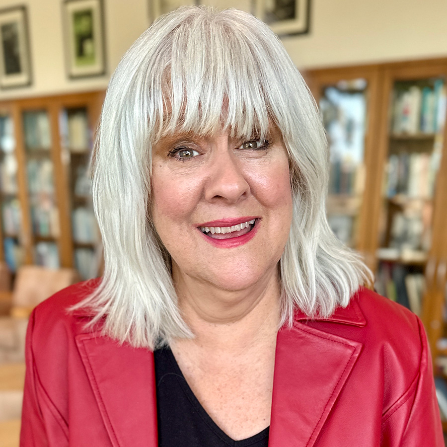 Headshot of Tere with books on bookshelves in background.