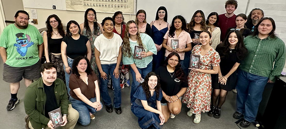 A group of students gather inside Music 160, some holding copies of the CWAA journal Flies, Cockroaches and Poets.