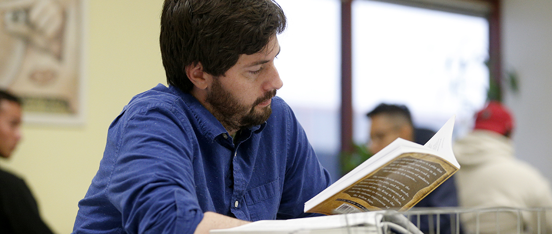 A graduate teaching associate reads while tutoring inside the Writing Center.