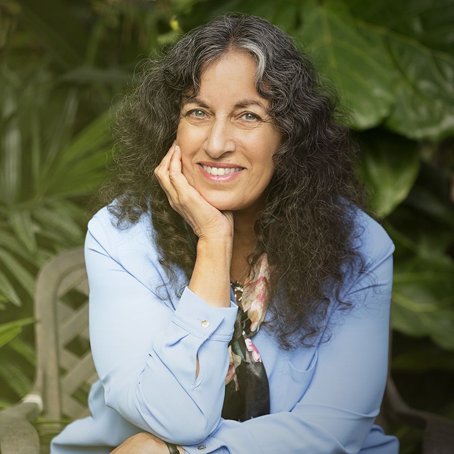Headshot of Margarita. She is wearing a light blue shirt, and there's greenery in background.