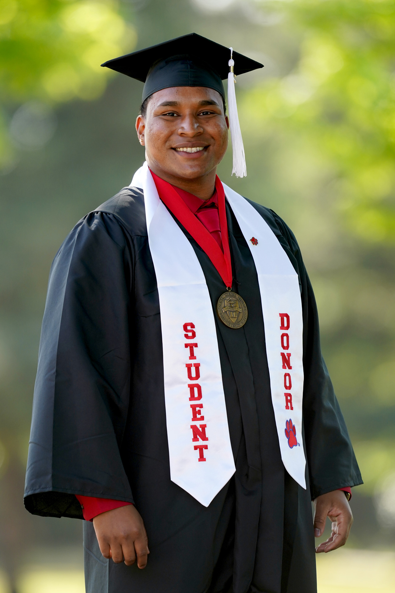 Undergraduate Dean's Medalist Caleb Charles stands with his graduation regalia and his student donor stole.