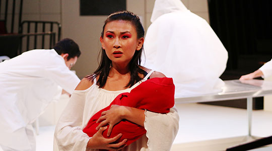 Student holds a baby during a theatre performance.