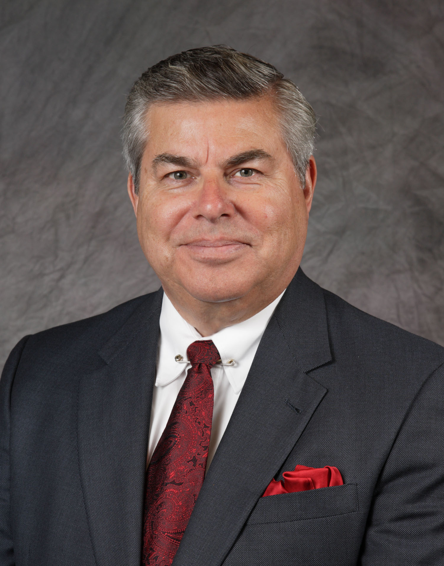 James A. Ardaiz headshot in a dark gray suit and red tie