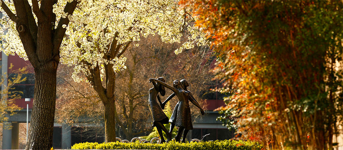 Three graces statue basked in fall colors.