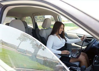 Reporter works on her laptop in her car. 