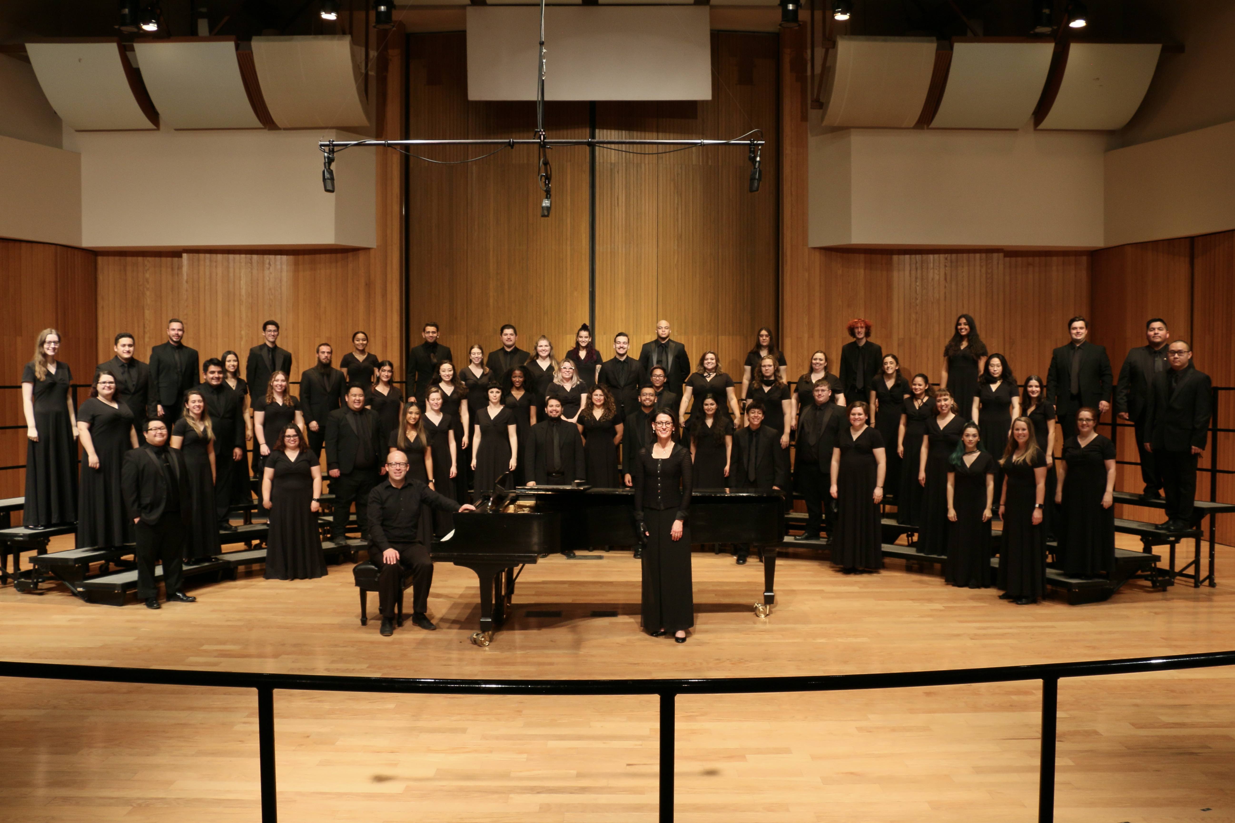 Fresno State Concert Choir on stage in the Concert Hall. Students are wearing all black and facing the camera.