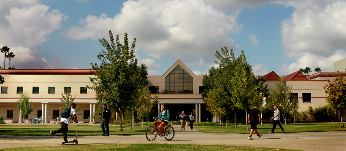 New music building with students walking and cycling through campus.