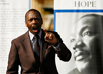 Professor Thomas Whit Ellis speaks at a Rev. Martin Luther King, Jr. event in front of an MLK banner.