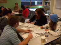 A tutor listens as a student reads his paper in a group.